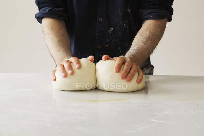 Baker shaping two portions of dough. — Stock Photo