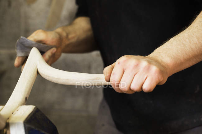 Homem lixando um pedaço de madeira curva — Fotografia de Stock