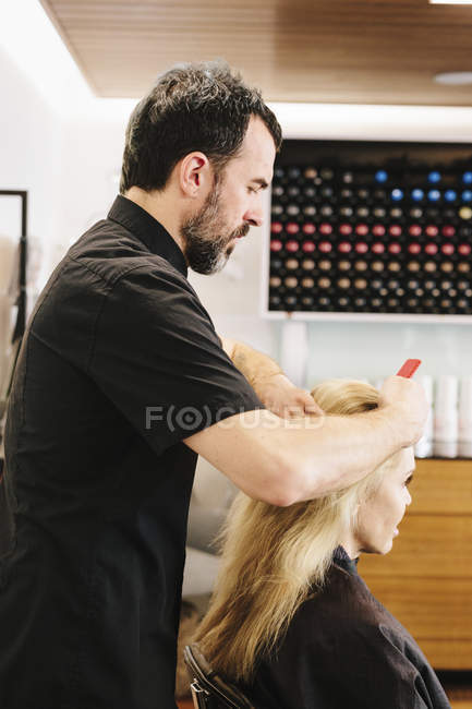 Hair stylist combing out a client's hair. — Stock Photo