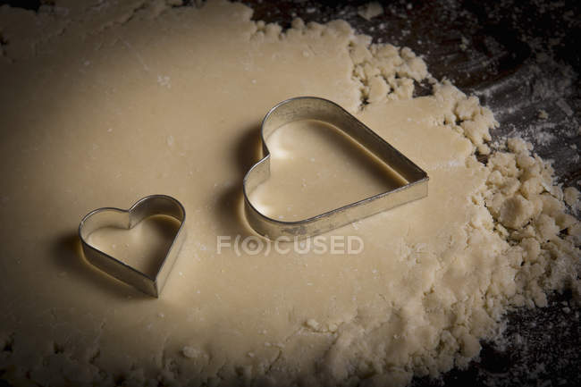Cortadores de galletas en forma de corazón en la masa - foto de stock