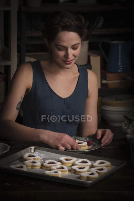 Woman sitting in kitchen with baking tray — Stock Photo