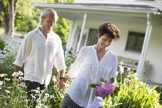 Älteres Paar spaziert durch Garten — Stockfoto