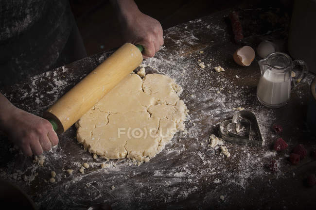 Femme déroulant la pâte avec rouleau à pâtisserie — Photo de stock