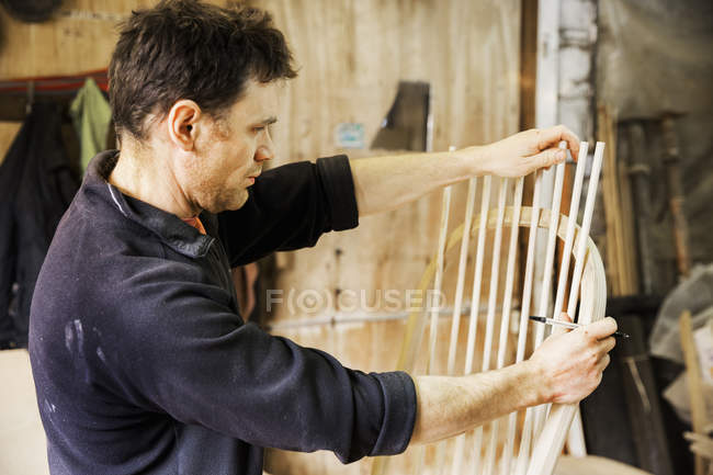 Hombre trabajando en una silla de madera . - foto de stock