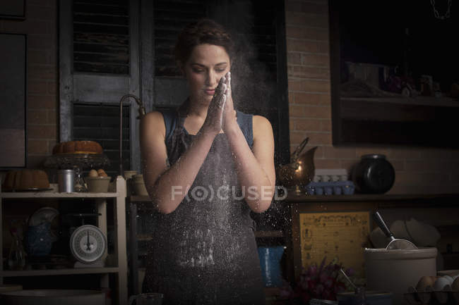Woman rubbing flour between hands — Stock Photo