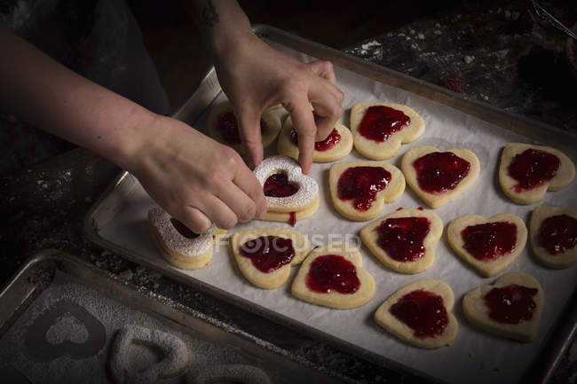 Woman spreading raspberry jam on biscuits — Stock Photo