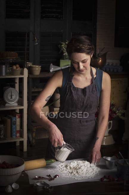 Mujer preparando masa y vertiendo leche - foto de stock