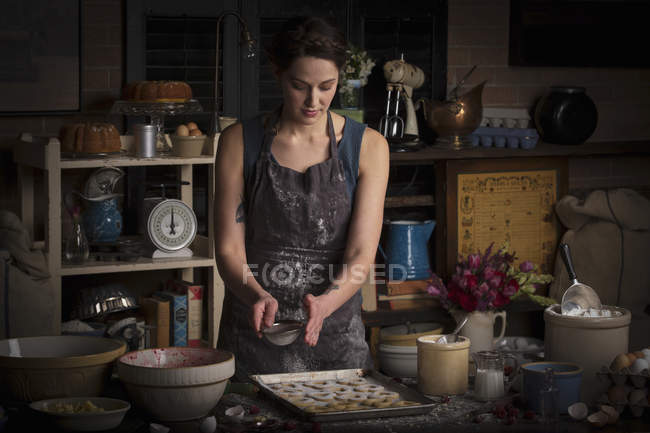 Женщина посыпает ледяным сахаром печенье — стоковое фото
