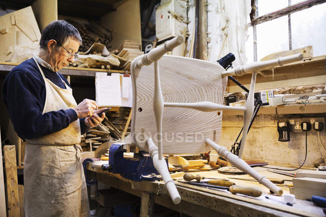 Hombre trabajando en una silla de madera - foto de stock
