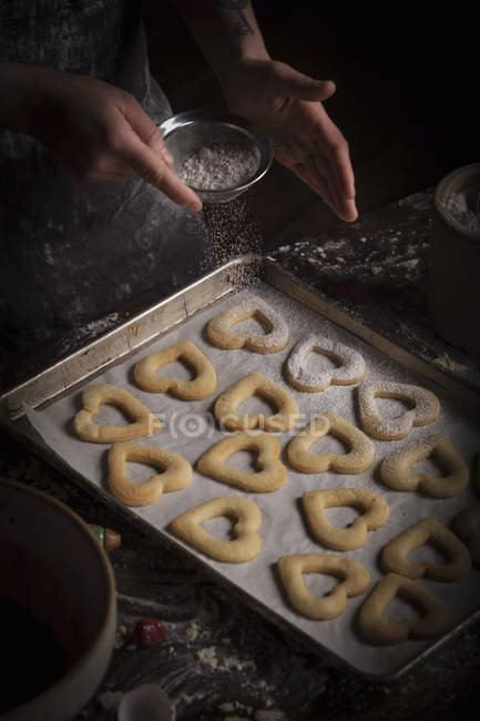 Mulher polvilhar açúcar de confeiteiro sobre biscoitos — Fotografia de Stock