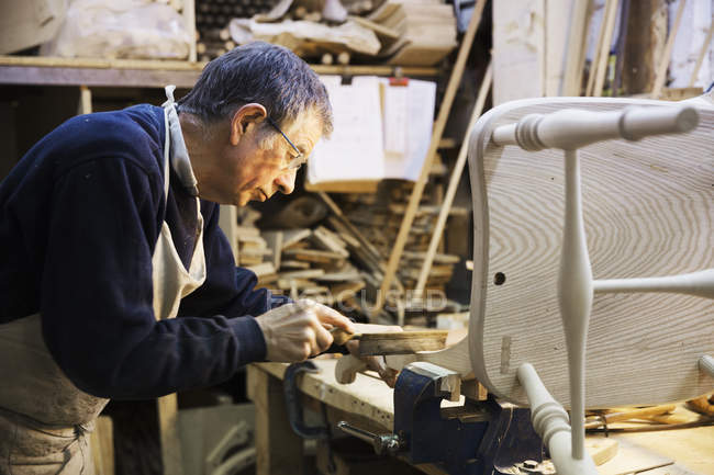 Hombre trabajando en una silla de madera - foto de stock