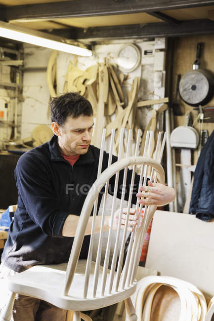 Man working on a wooden chair back. — Stock Photo