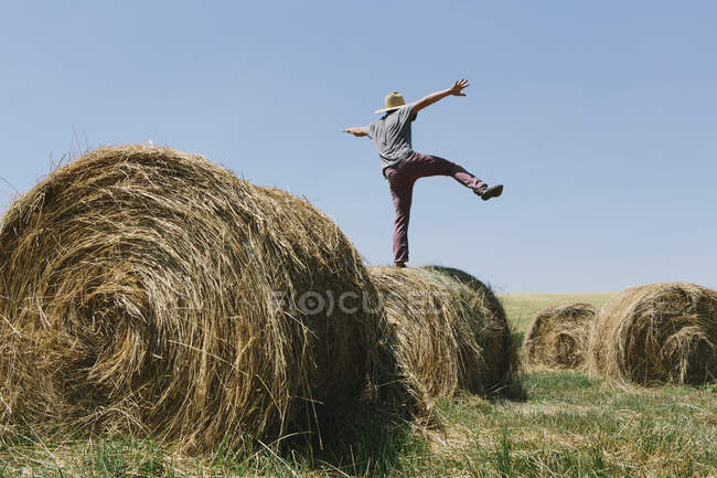 Man balancing on hay bale — Stock Photo