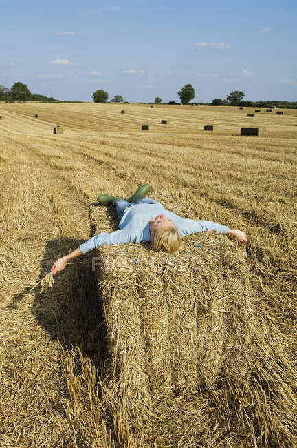 Woman lying on top of square bale — Stock Photo