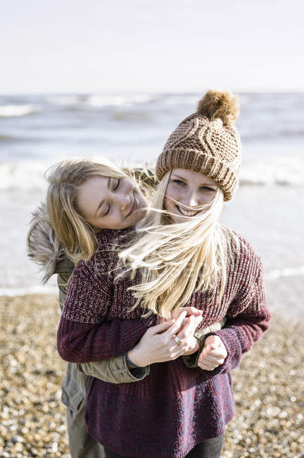 Дівчата обіймають один одного на пляжі — стокове фото