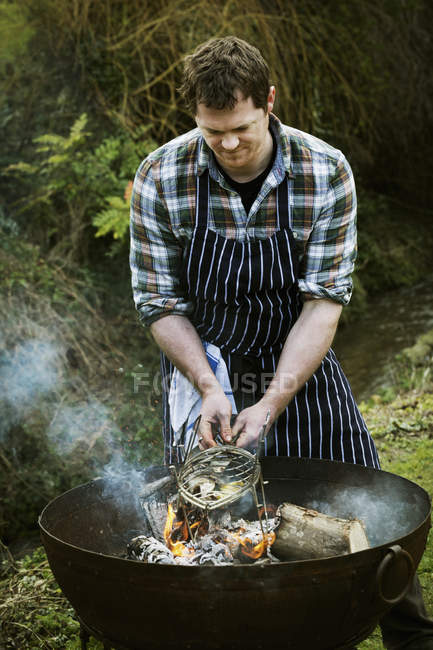 Chef grilling a fish on a barbecue. — Stock Photo