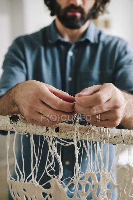 Artista masculino anudando y tejiendo hilos . - foto de stock