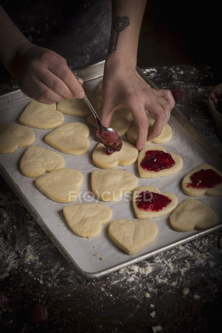 Mujer propagación de mermelada de frambuesa en galletas - foto de stock