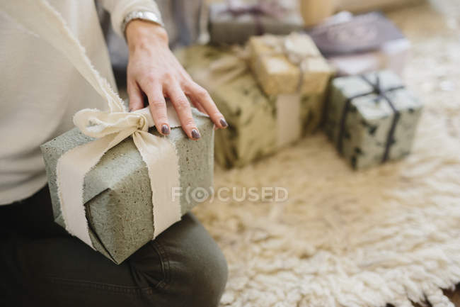 Frau sitzt mit Stapel verpackter Geschenke — Stockfoto
