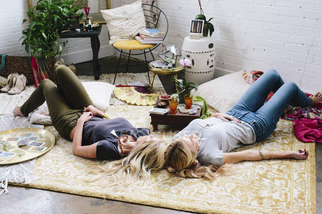 Femmes couchées sur le sol avec des coussins et des effets personnels — Photo de stock
