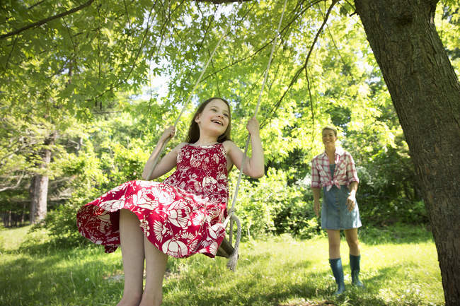 Mädchen schaukeln unter begrüntem Baum — Stockfoto