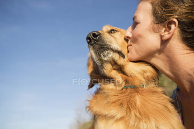 Mujer besando a un perro - foto de stock
