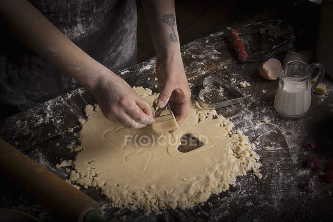 Woman cutting out heart shaped biscuits — Stock Photo