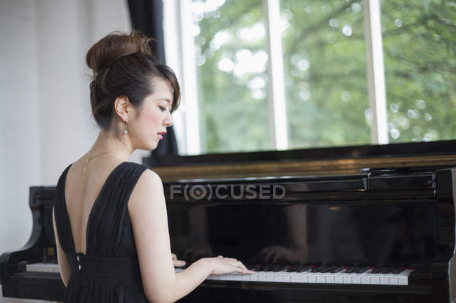 Mulher tocando em um piano de cauda — Fotografia de Stock