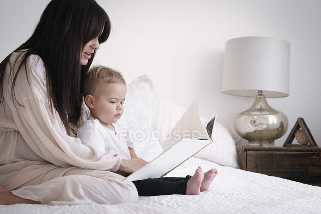 Беременная женщина читает с сыном — стоковое фото