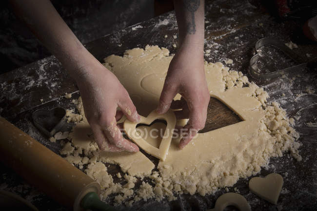 Woman cutting out heart shaped biscuits — Stock Photo