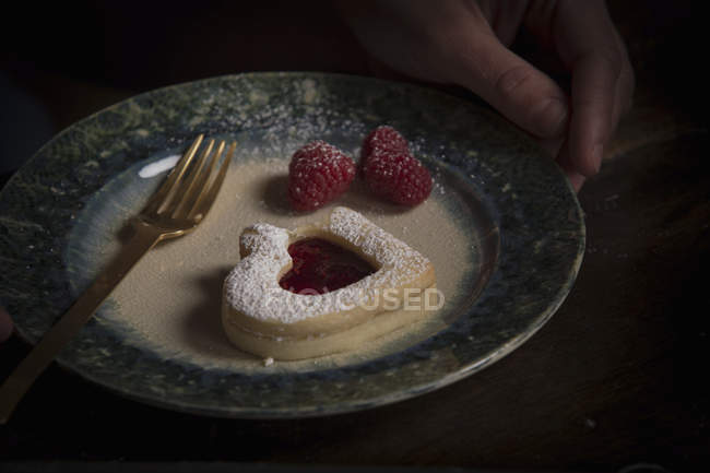 Plate with heart shaped biscuit and raspberries — Stock Photo