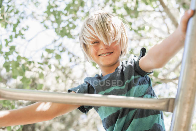 Chico en escalada marco en jardín - foto de stock