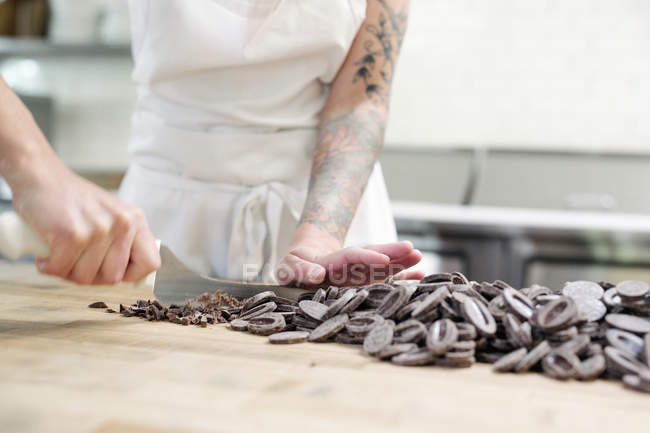 Woman chopping chocolate in bakery — Stock Photo