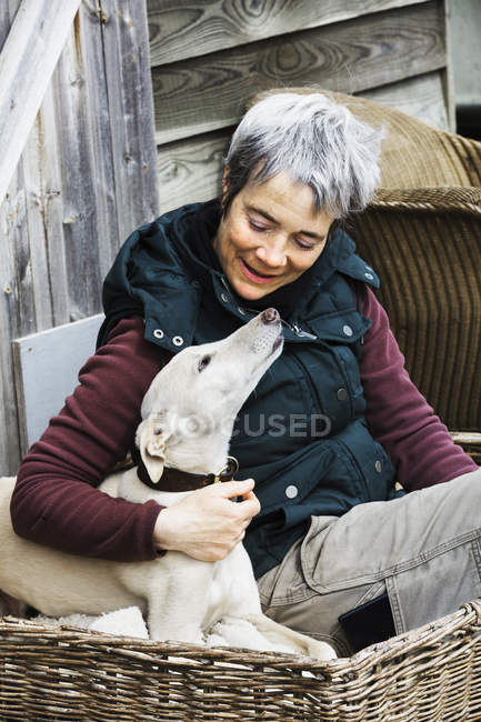 Woman sitting beside a greyhound dog — Stock Photo