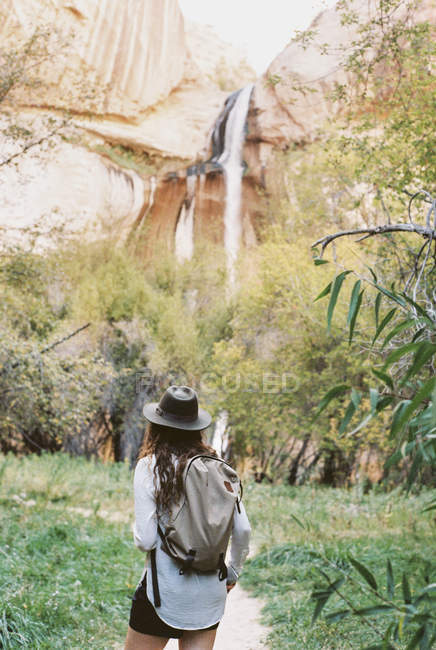 Woman with backpack under a tall cliff — Stock Photo