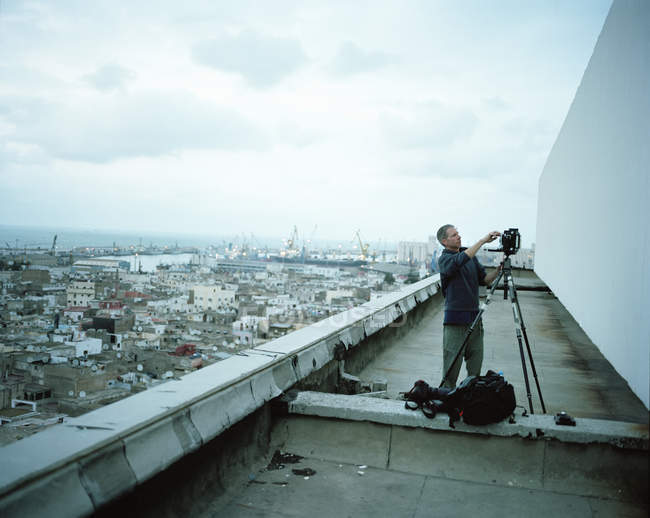 Photographe debout sur un toit dans une ville — Photo de stock