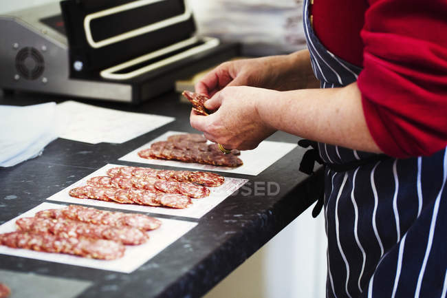 Butcher packaging slices of salami — Stock Photo