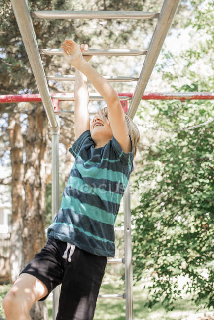 Boy on climbing frame in garden — Stock Photo