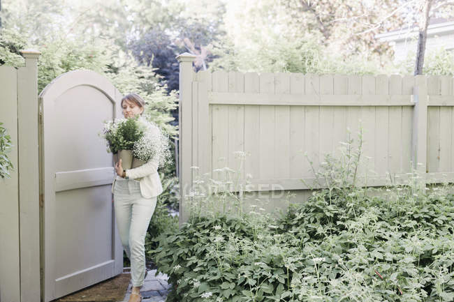 Mujer entrando en un jardín a través de una puerta - foto de stock
