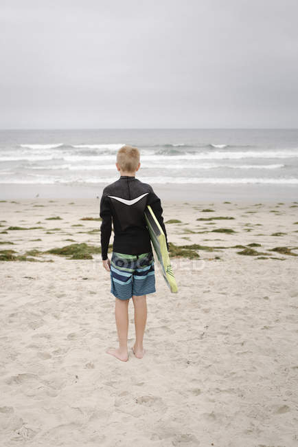 Menino de pé na praia arenosa — Fotografia de Stock