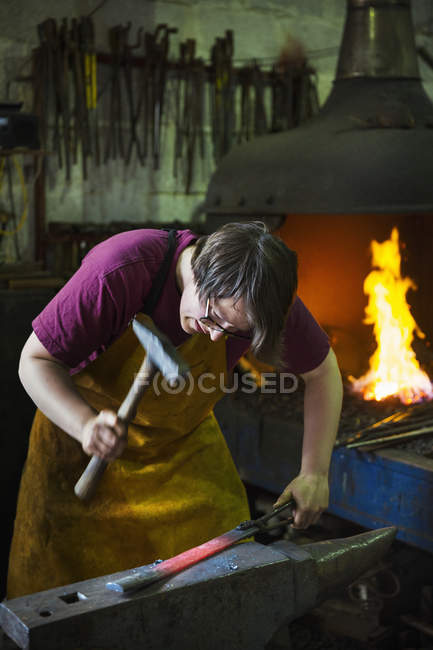 Blacksmith with a hammer in a workshop. — Stock Photo