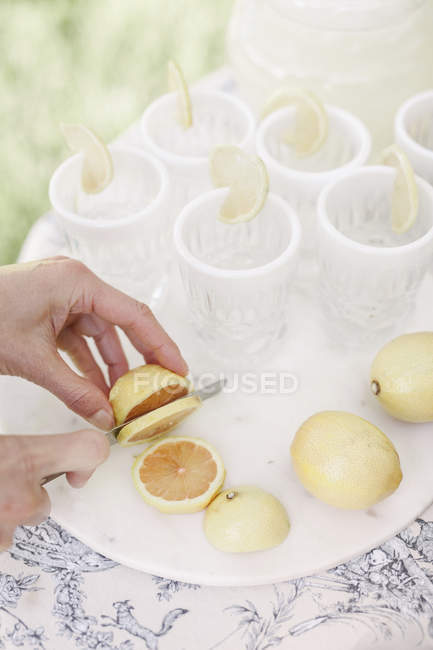 Woman slicing lemons for a drink. — Stock Photo