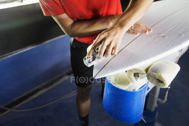 Mann arbeitet in Werkstatt an einem Surfbrett. — Stockfoto
