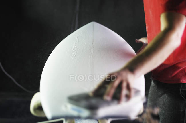 Man working on a surfboard in a workshop. — Stock Photo