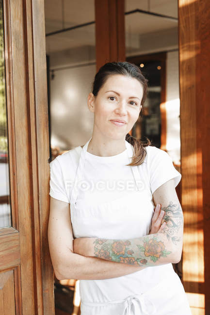 Woman standing with arms crossed in doorway — Stock Photo