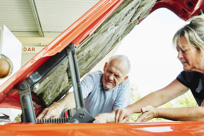 Mujer y hombre mayor reparando un coche - foto de stock