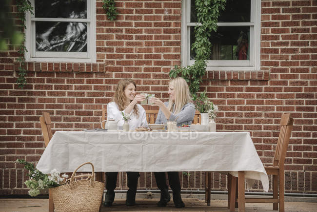 Mujeres fuera de una casa teniendo una comida . - foto de stock
