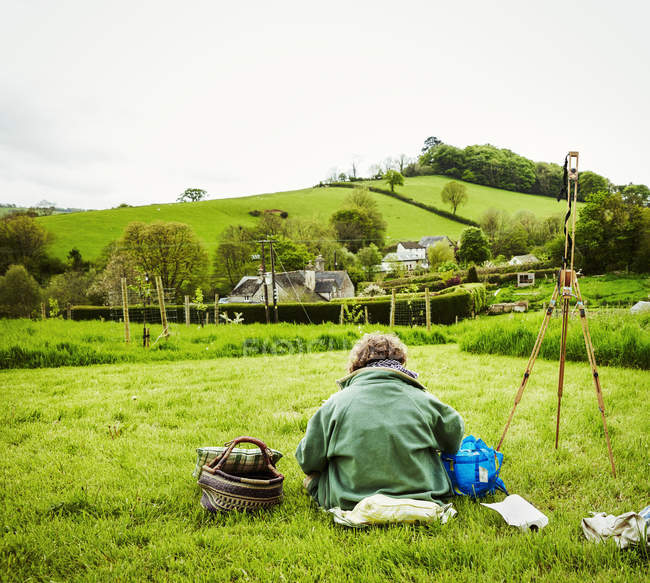 Woman artist working outdoors in landscape — Stock Photo