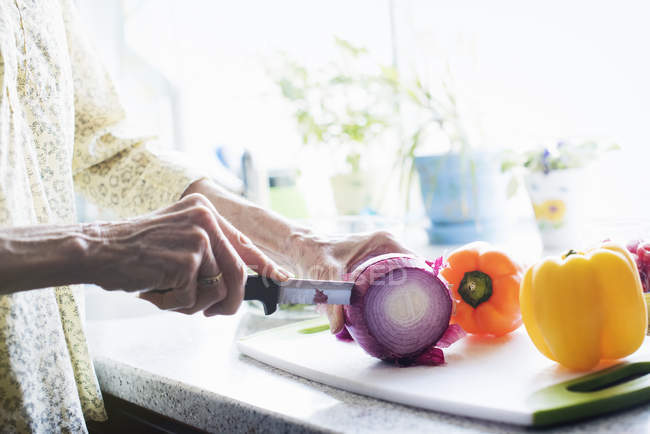 Woman cutting a red onion — Stock Photo