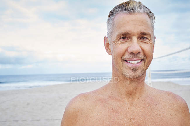 Hombre maduro de pie en una playa - foto de stock